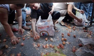 People crouch to collect leftover vegetables in Athens